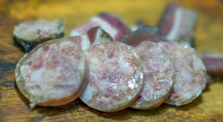 Sliced sausages and appetizing slices of lard lie on a wooden tray, as an example of unhealthy and high-calorie food.の写真素材
