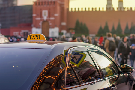 a taxi parked on the sidewalk of a large street with large traffic jams and many people, the car reflects the lights of the night city Moscowの写真素材
