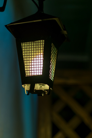 Old lantern in a dark alley. Hangs on a wooden wall background.の写真素材