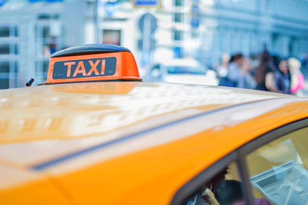 Checker taxi on the roof of a yellow car in the center of a big city waiting for passengers in the big cityの写真素材