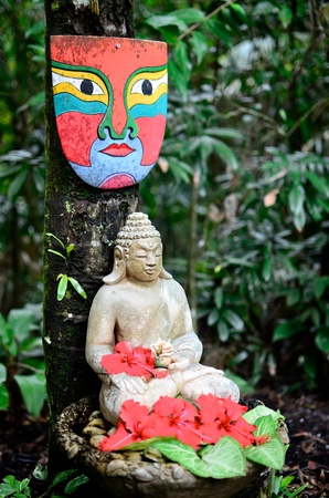 A buddha statue and mask in a garden の写真素材