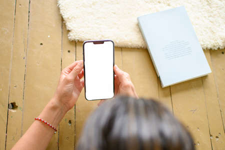Top view of a young caucasian woman holding the mobile with white screen. Horizontal. With copyspace.の写真素材