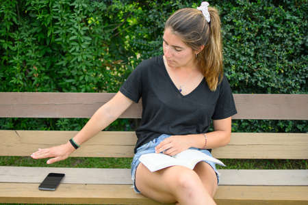 Young caucasian woman leaving her mobile phone and choosing literature. Horizontal. With copyspace.の写真素材