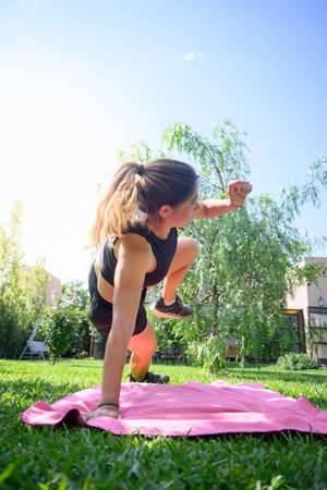 Front view of a caucasian woman doing some exercise in her home garden. Vertical. With copy space.