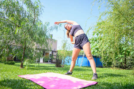 Caucasian woman stretching before doing workout in her home garden. Horizontal. With copyspace.