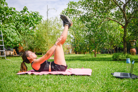 Caucasian woman doing some workout in her home garden. Horizontal. With copyspace. Stretching her...