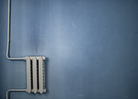 heating radiator on blue wall background texture with copy space for text or image