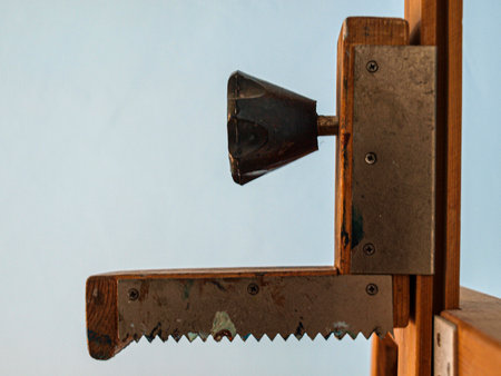 Vintage hand saw on a wooden shelf against a blue wall.