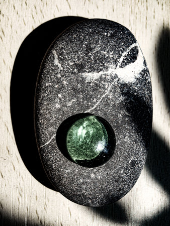 black and white photo of a stone with a green pebble