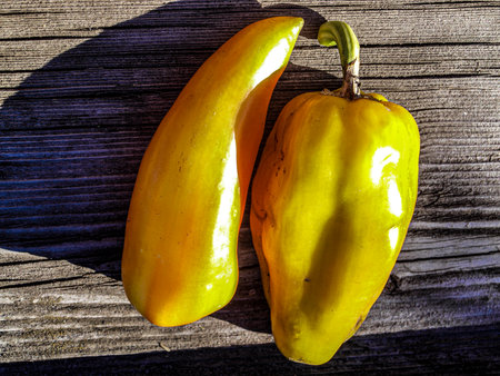 Two yellow peppers on a wooden background. Top view. Toned.