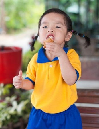 Little girl eating chickenの写真素材