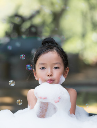 asian little girl playing with water and foamの写真素材