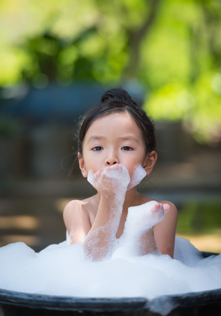 asian little girl playing with water and foamの写真素材