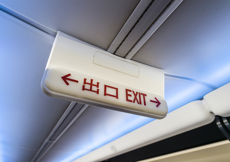 Exit sign in English and Chinese language on airplaneの写真素材