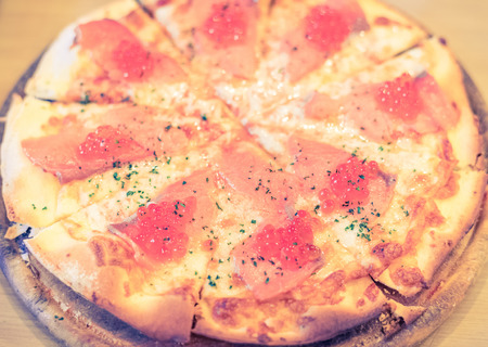 Pizza with smoked salmon and red salted caviar, retro vintage filter effectの写真素材