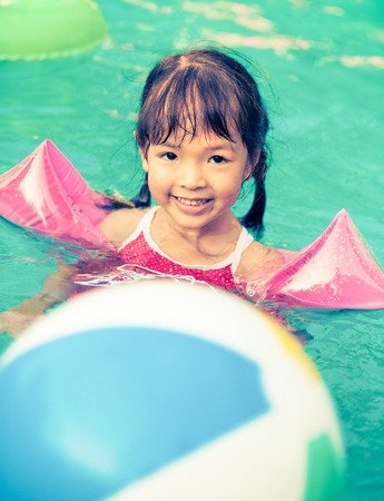 Little girl swimming in pool, retro vintage filter effectの写真素材