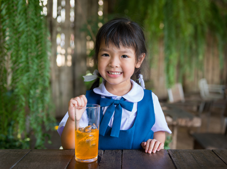 Little school girl drinking orange juiceの写真素材