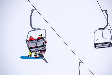 Snowboarder and skier on ski lift seen from belowの写真素材