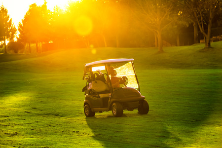 Golf cart with sun set on golf courseの写真素材