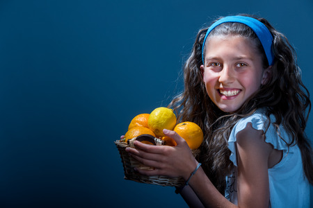 Young girl with a fruit basket. Isolated on dark backgroundの写真素材