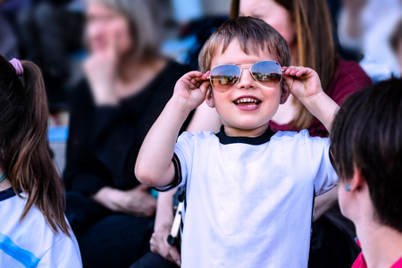 Smiling child wearing sunglasses standing in the stadiumの写真素材