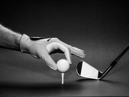 Man's hand positioning a golf ball