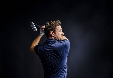 Golf player golfing in studio isolated on dark backgroundの写真素材