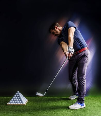 Golf player practicing in a driving range with pyramid of golf ballsの写真素材