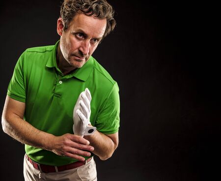 Closeup of a male golfer put on a glove. Horizontal format over a black background.の写真素材