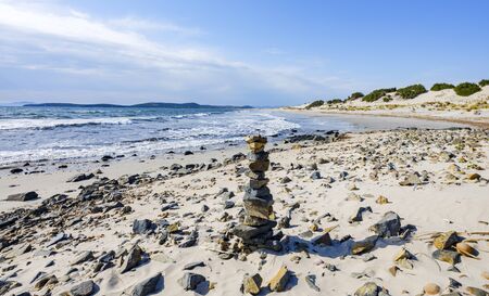 Stack of pebbles stone on the beach of Porto Pino, Sant'Anna Arresi, Sardinia, Italy. Background for balance, meditation and zen theme.の写真素材