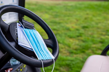 Protective anti Covid-19 mask resting on the steering wheel of the golf carの写真素材