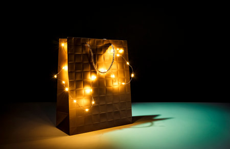 Gold illuminated shopping bag on black background. Black Friday concept. Idea of gifts, deals, sales, event.の写真素材
