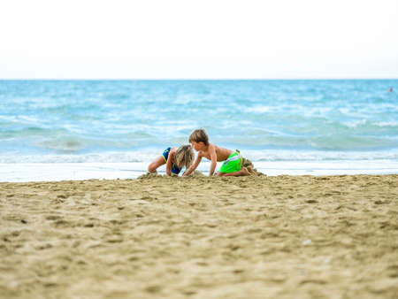 The child in a bathing suit plays on the sand at the beach on a sunny day.の写真素材
