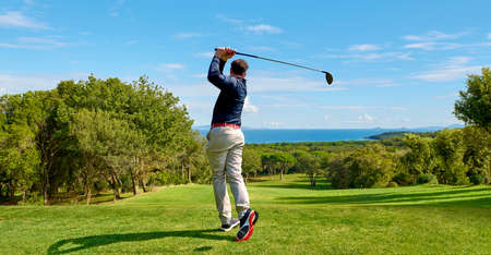 Golfer on the professional golf course. Golfer with golf club hitting the ball for the perfect shot.の写真素材