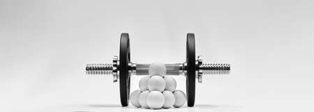 Golf balls with dumbbell and iron weights on white background. Training concept for more strength.の写真素材