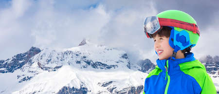 Smiling child on the high altitude ski slope in the Italian Alps. Happy child with helmet and ski goggles on the ski slopes.の写真素材