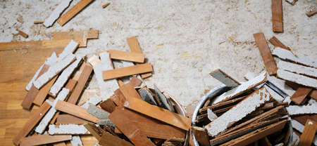 Craftsman in workwear removes the parquet flooring and fills the buckets with the wooden slats...