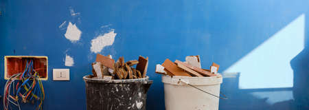 Parquet in wood glued to the slab, removed with an electric demolition hammer, in the apartment under renovation. The strips of the removed parquet are placed in a container to be disposed of. You work around the house to improve energy efficiency.の写真素材