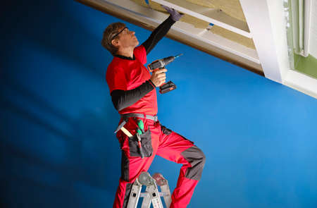 Rock wool applied to a wooden attic under renovation to save energy. Craftsman with work tools,...