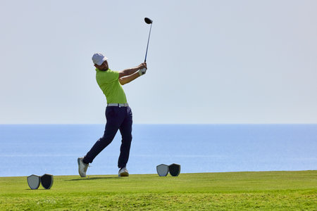 Golfer on a golf course, ready to tee off. Golfer with golf club hitting the ball for the perfect shot.の写真素材
