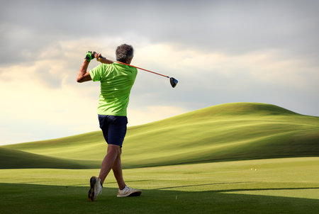 Golfer on a golf course, ready to tee off. Golfer with golf club hitting the ball for the perfect shot.の写真素材