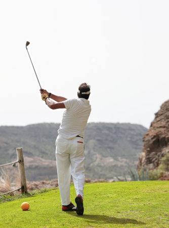 Golfer on a golf course, ready to tee off. Golfer with golf club hitting the ball for the perfect shot.の写真素材