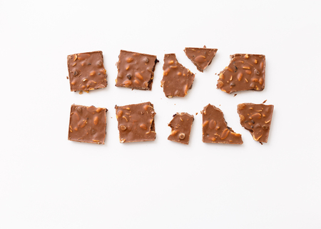 Roughly broken milk chocolate on colorful white background, top view flat lay. Concepts about decoration, food backgroundの写真素材