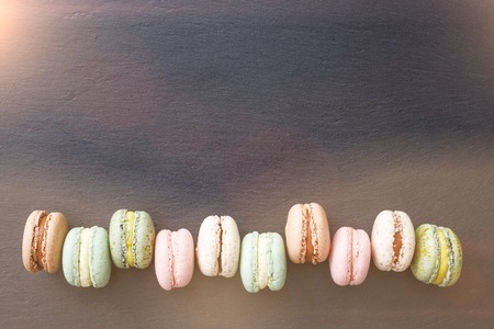 Colorful macarons cake, top view flat lay, sweet macaroon on dark black marble, text background. Minimal concepts macaroons above, food backgroundの写真素材