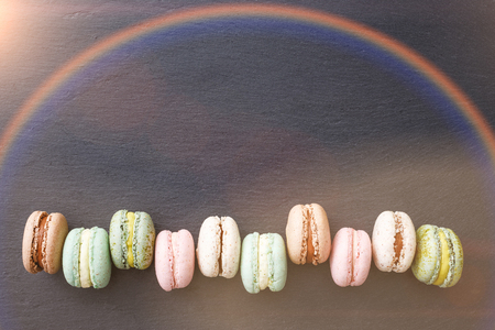 Colorful macarons cake, top view flat lay, sweet macaroon on black marble, text background. Minimal rainbow conceptsの写真素材