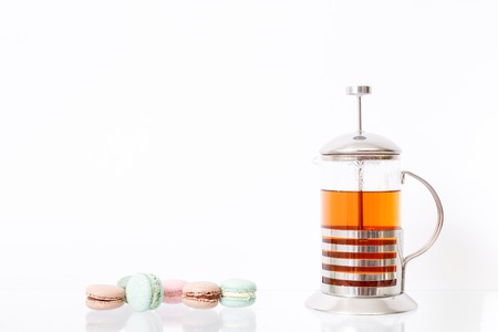 Colorful macarons cake and hot morning tea in glass teapotsの写真素材