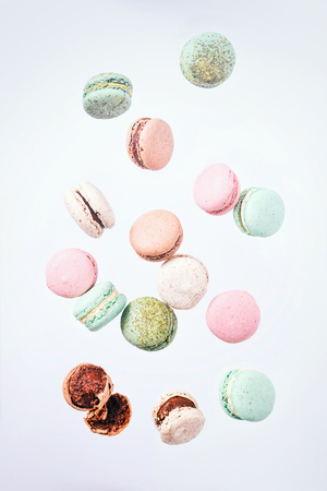Colorful macarons cake, top view flat lay, fly falling sweet macaroon on color white isolated background. Minimal concepts falling macaroons pattern above, food backgroundの写真素材