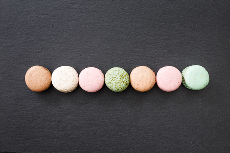 Colorful macarons cake, top view flat lay, sweet macaroon on black marble background. Minimal concepts macaroons pattern above, food backgroundの写真素材