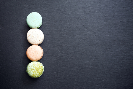 Colorful macarons cake, top view flat lay, sweet macaroon on black marble background. Minimal concepts macaroons pattern above, food backgroundの写真素材