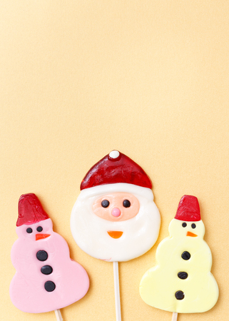 Lollipops new year sweets. Candy christmas snowman, top view flat lay on yellow background. Sweet sucker, lollipop snowman, candy, isolated minimal concept above decoration, new year food backgroundの写真素材